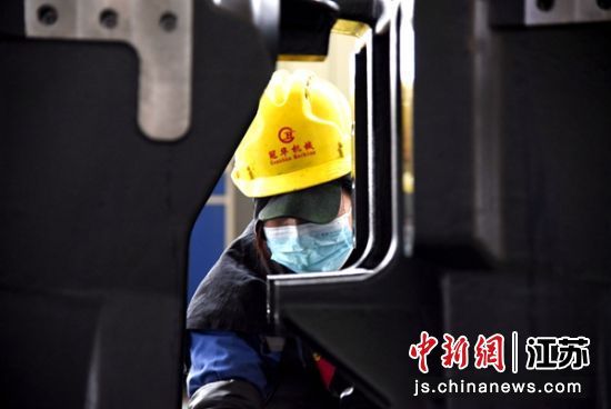 车间工人对即将出厂的大型拖拉机托架进行包装。朱志庚 摄